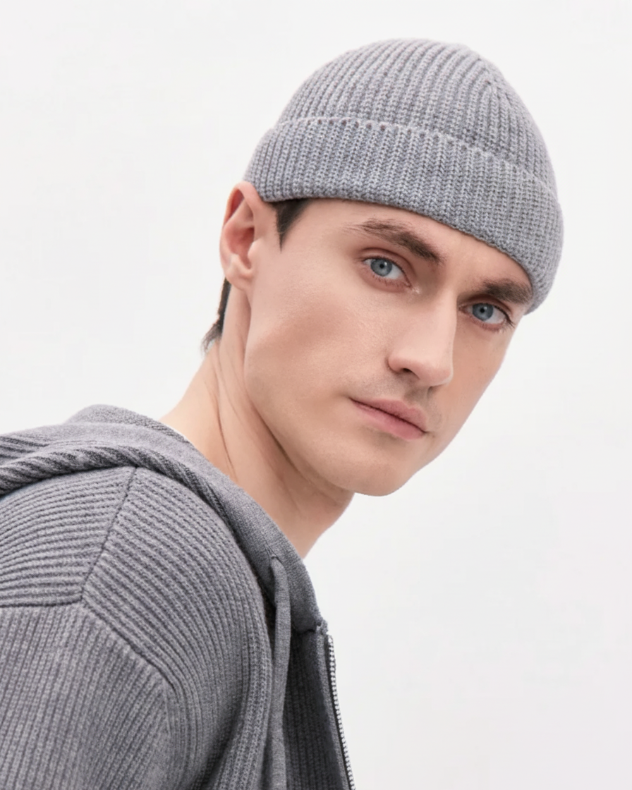 Man wearing a gray knit beanie and sweater against a light gray background