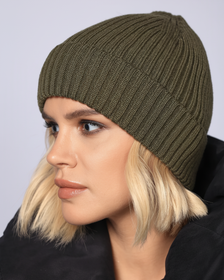 Woman wearing a green knit beanie against a plain background