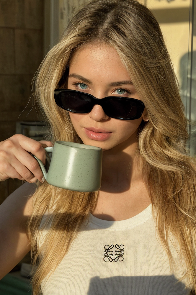 Woman with sunglasses holding a mug outdoors
