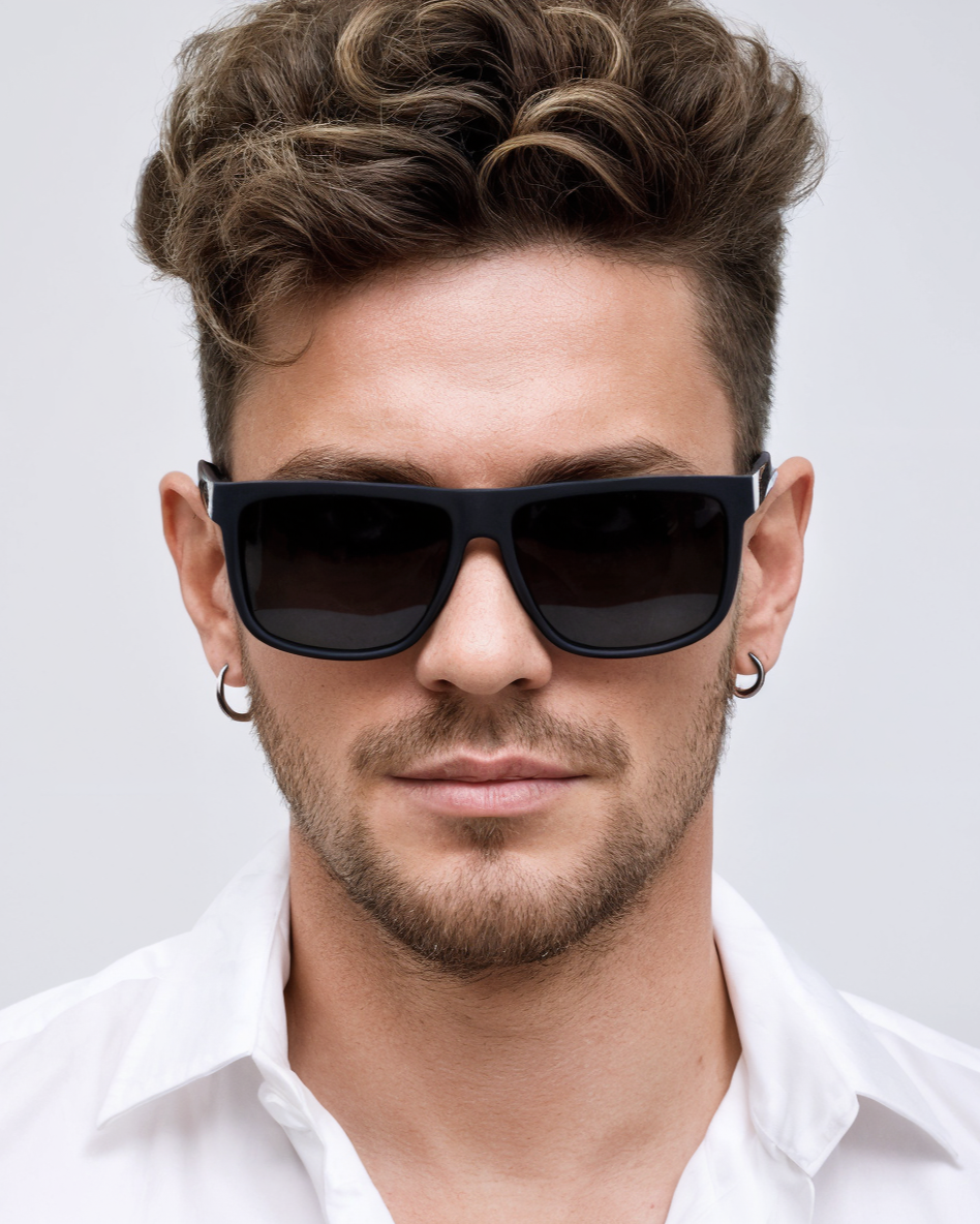 Man wearing black sunglasses and a white shirt against a light gray background