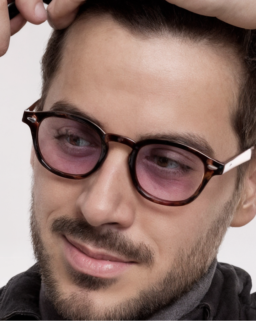 Man adjusting glasses with a neutral background