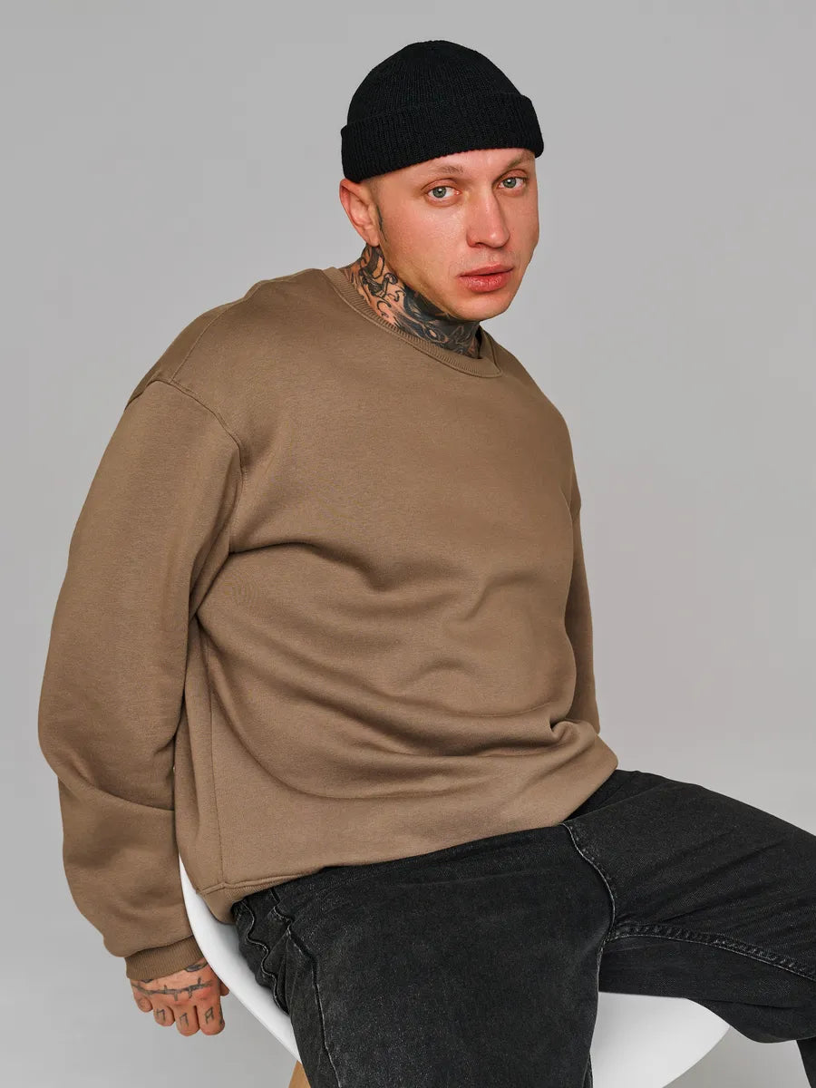 Person wearing a brown sweater and black pants against a gray background
