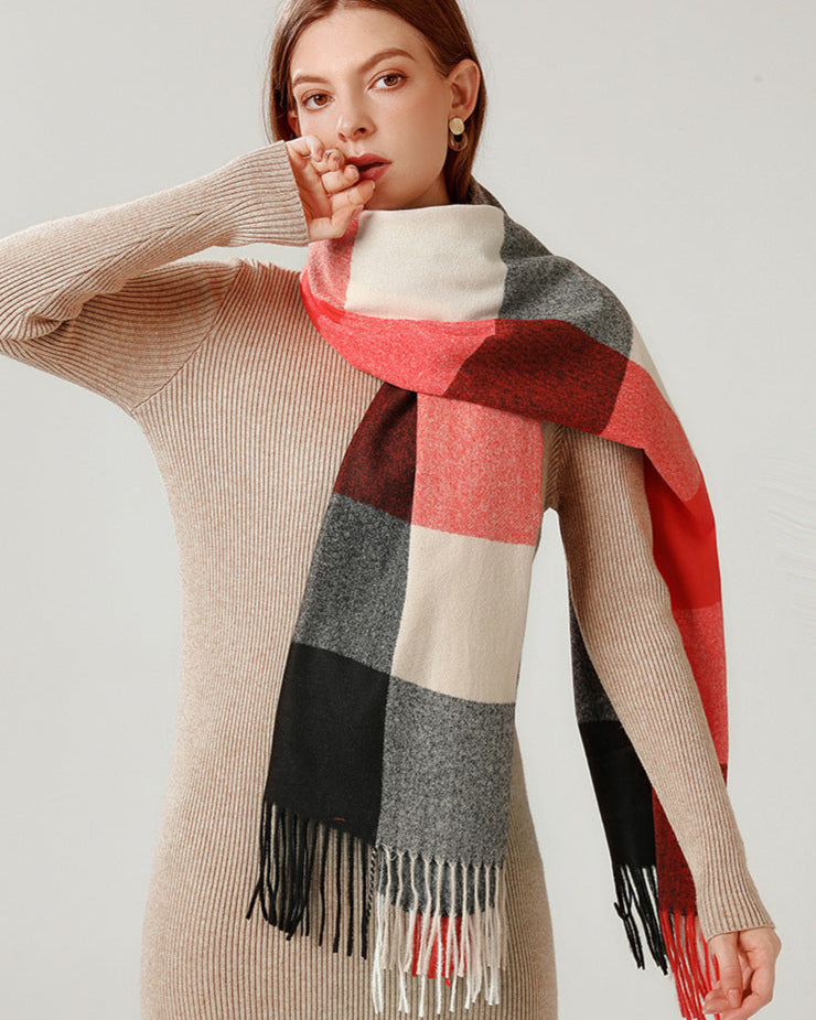 Woman wearing a checkered scarf with red, gray, and black pattern on a plain background