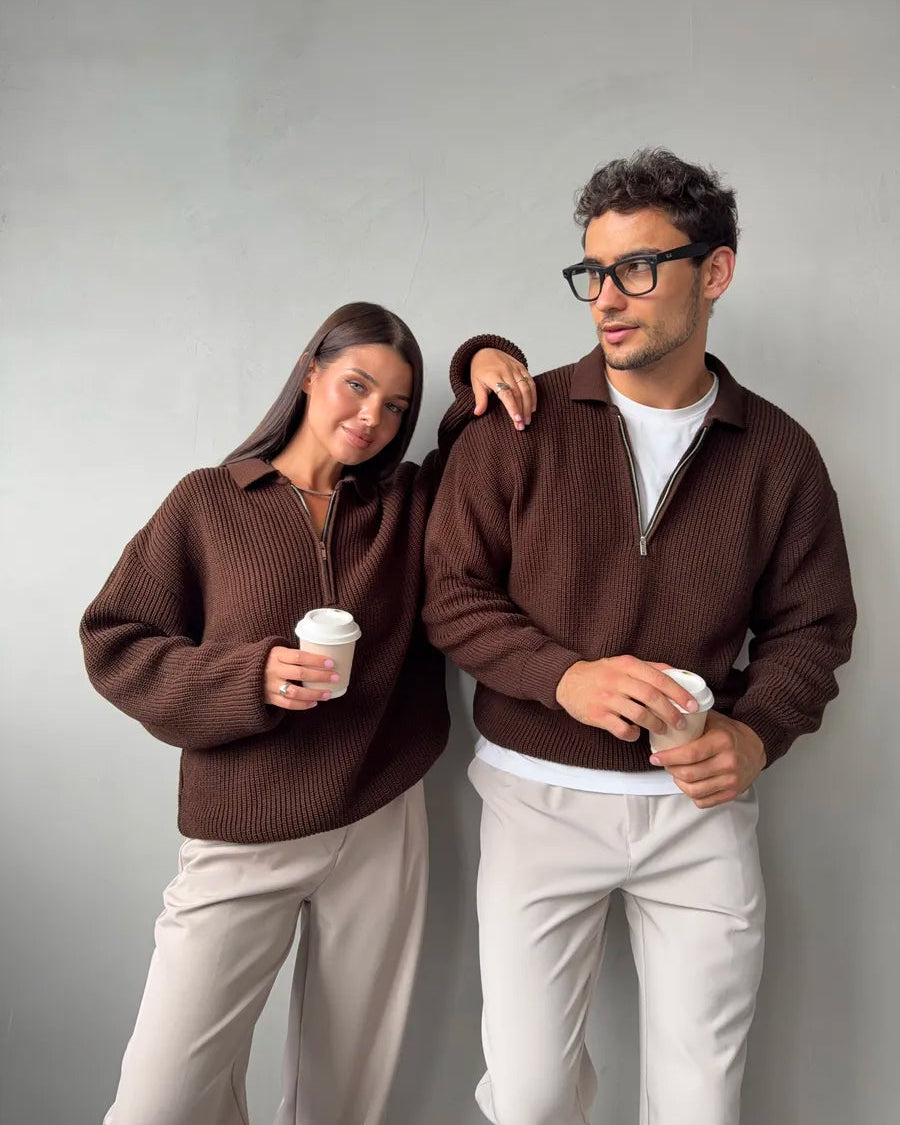 Two people wearing matching brown sweaters against a gray background