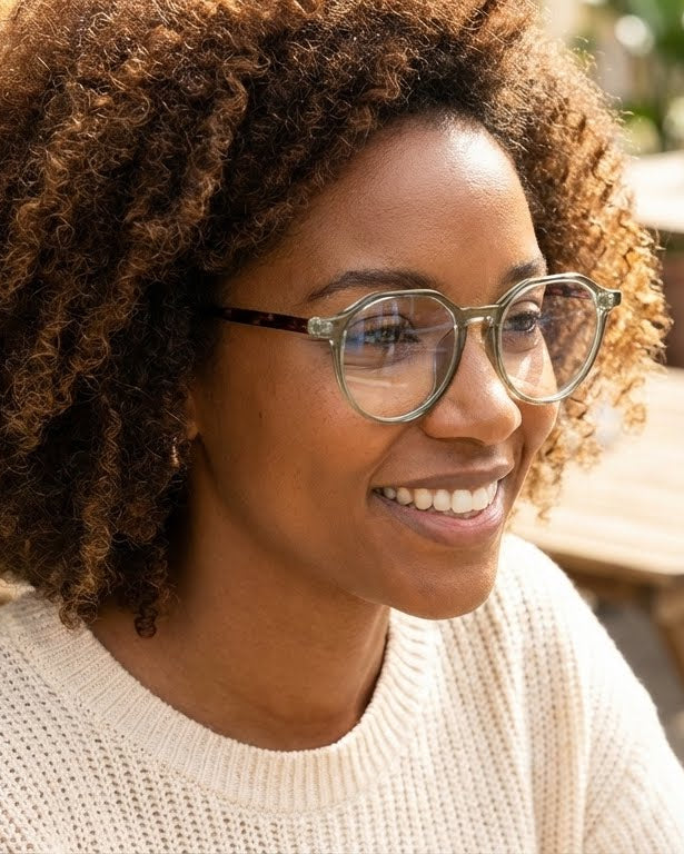 Woman with glasses smiling outdoors in a casual setting
