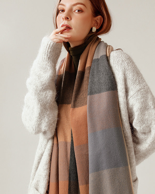 Woman wearing a plaid scarf and light gray cardigan against a plain background