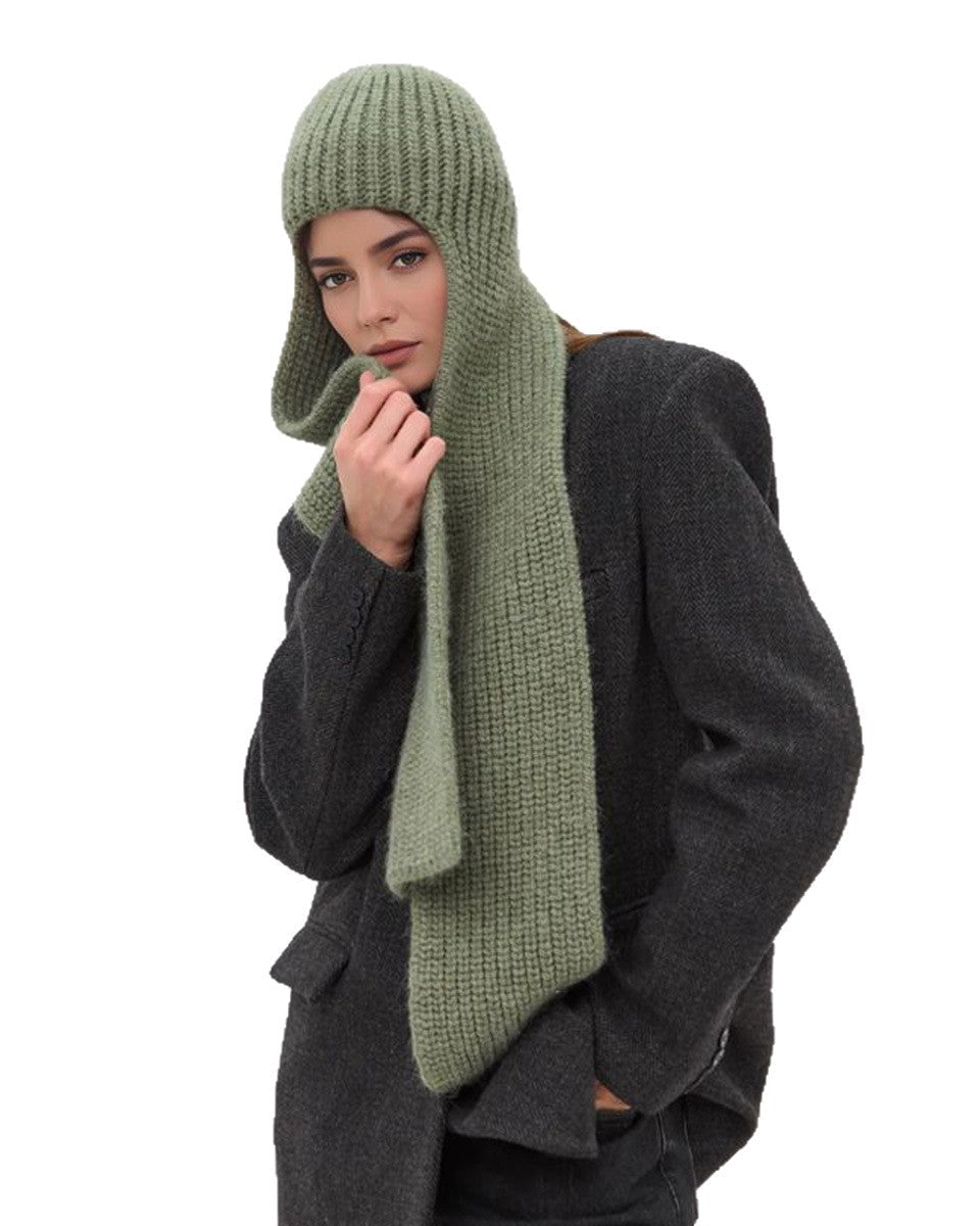 Person wearing a long green knitted scarf and hat on a white background