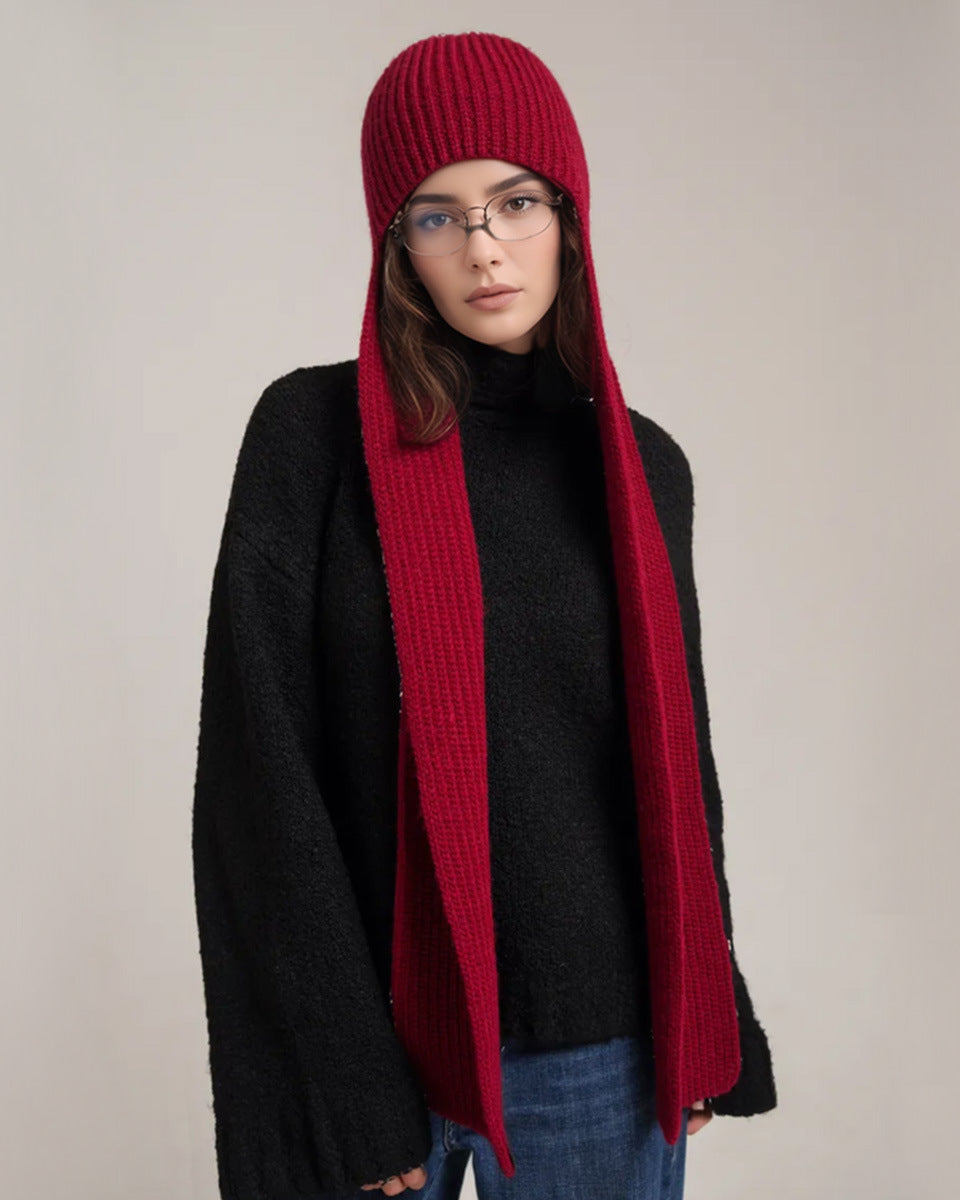 Person wearing a long red scarf and black coat on a plain background