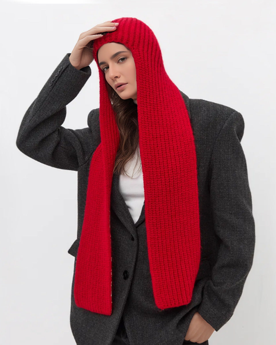 Person wearing a long red knitted scarf with a plain background