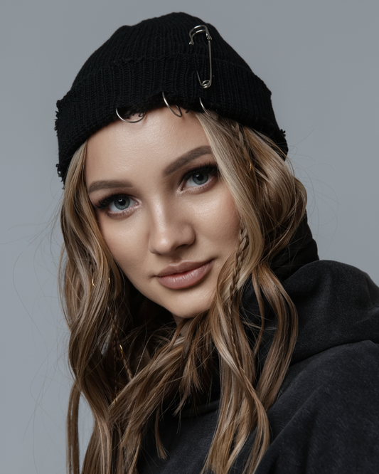 Person wearing a black knit hat and dark hoodie against a gray background