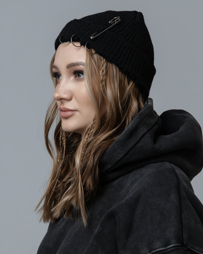 Woman wearing a black beanie and hoodie against a gray background