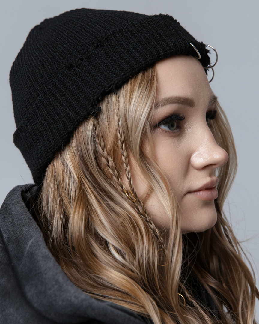 Person wearing a black knit beanie and gray hoodie against a neutral background