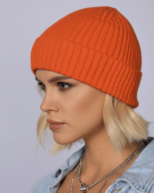 Person wearing an orange knit beanie and denim jacket against a light gray background