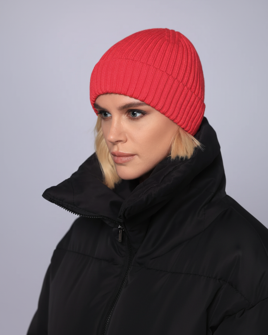 Person wearing a red beanie and black coat against a gray background