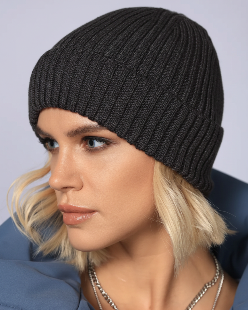 Person wearing a black knit beanie against a neutral background