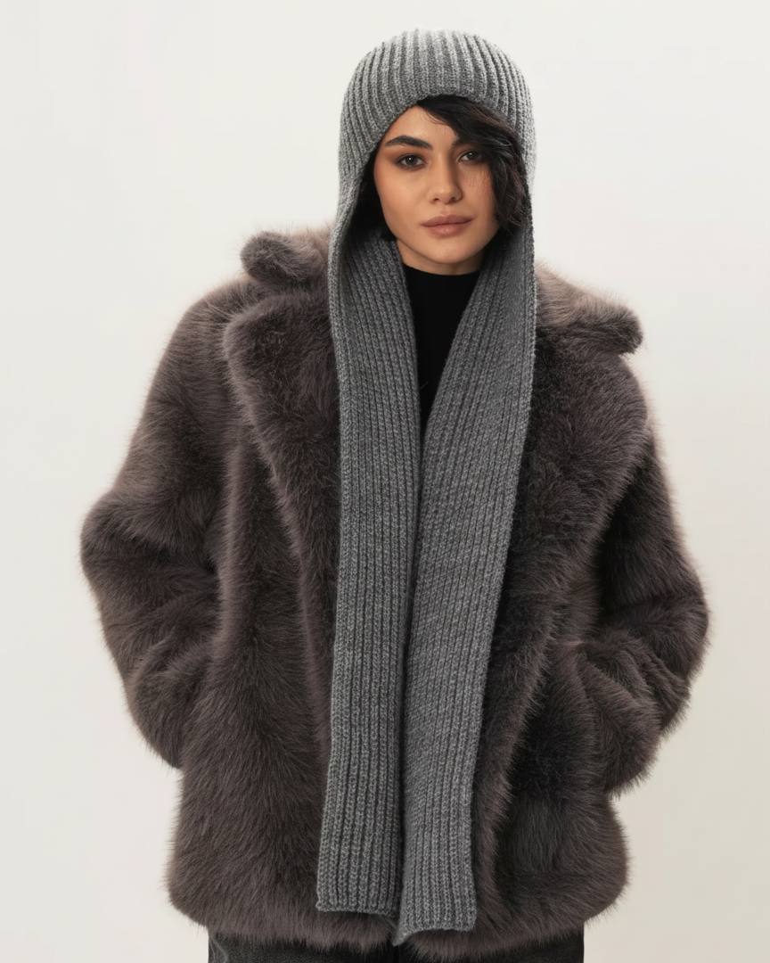 Person wearing a fluffy brown coat, gray knit hat, and scarf on a white background