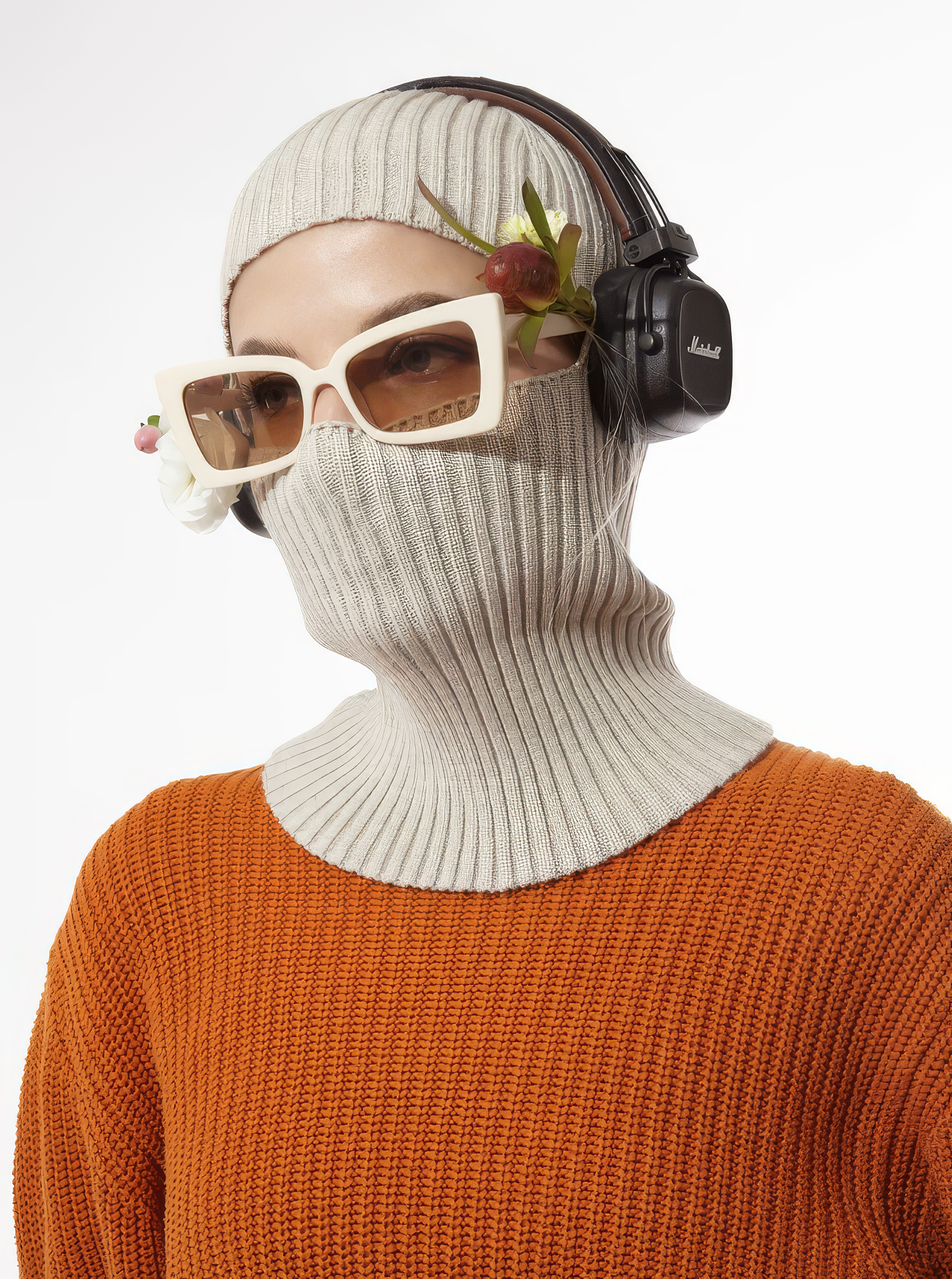 Person wearing a white knit balaclava, sunglasses, and headphones with a white background