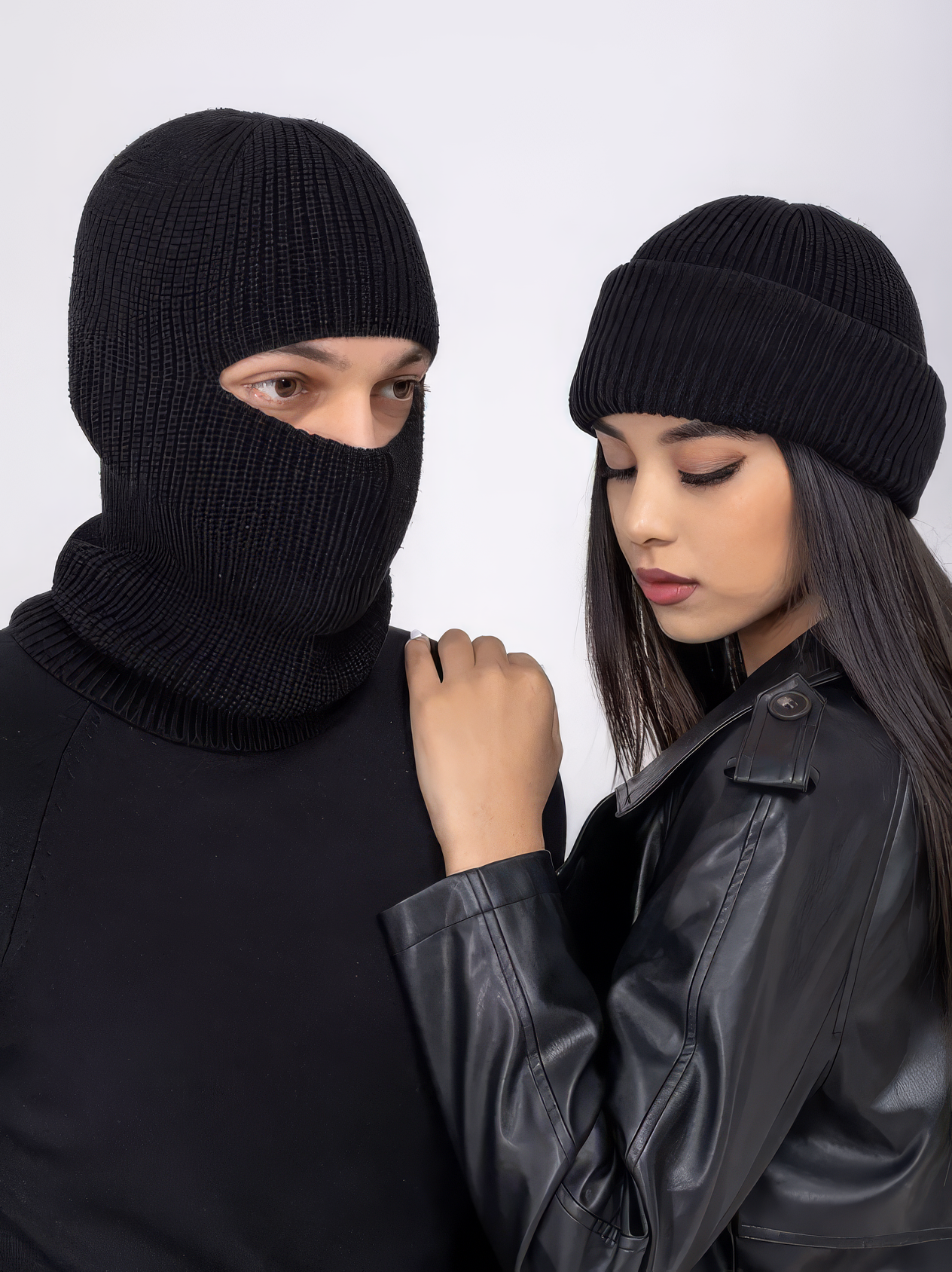 Two people wearing black knit hats against a white background