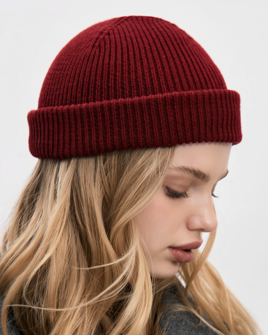 Woman wearing a red knit beanie against a plain background