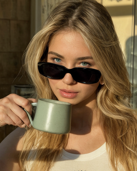 Woman with sunglasses holding a mug outdoors