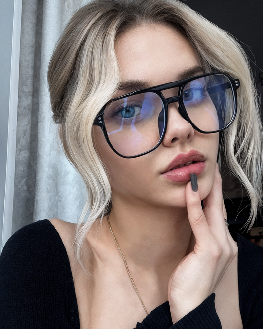 Woman wearing large black glasses with a blurred background
