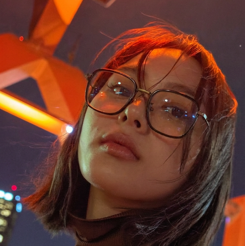 Person wearing glasses with a cityscape background at night