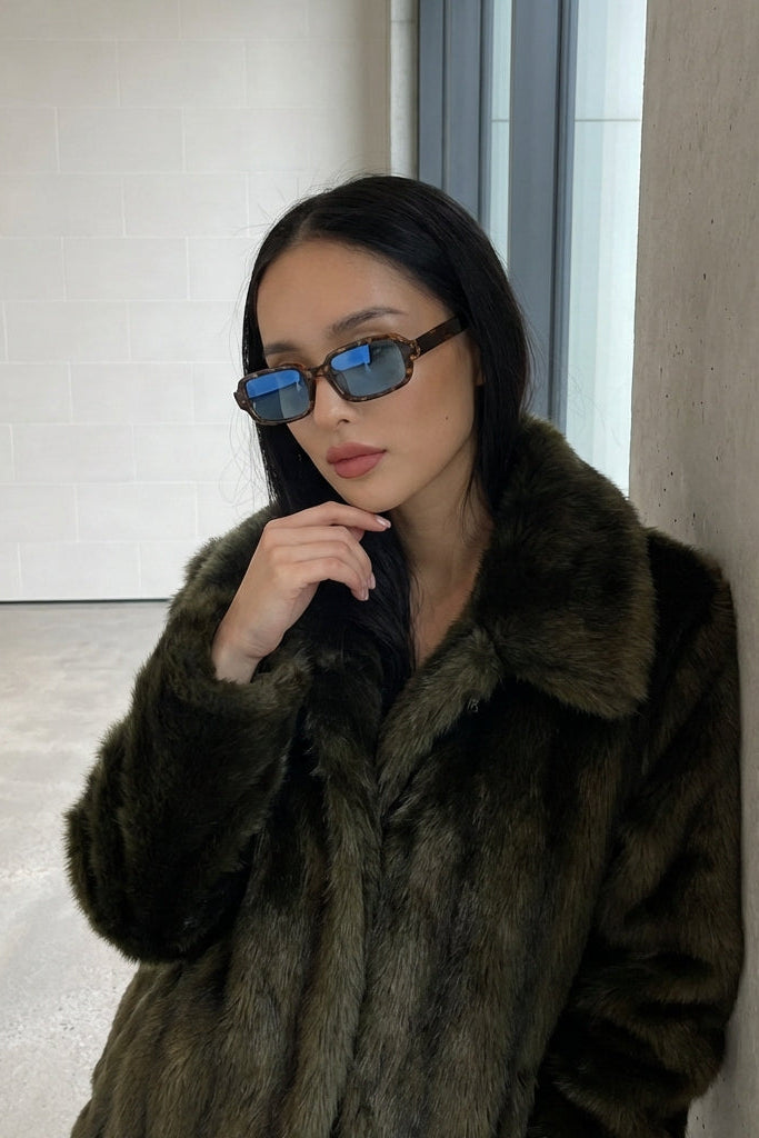 Woman wearing a fur coat and sunglasses indoors