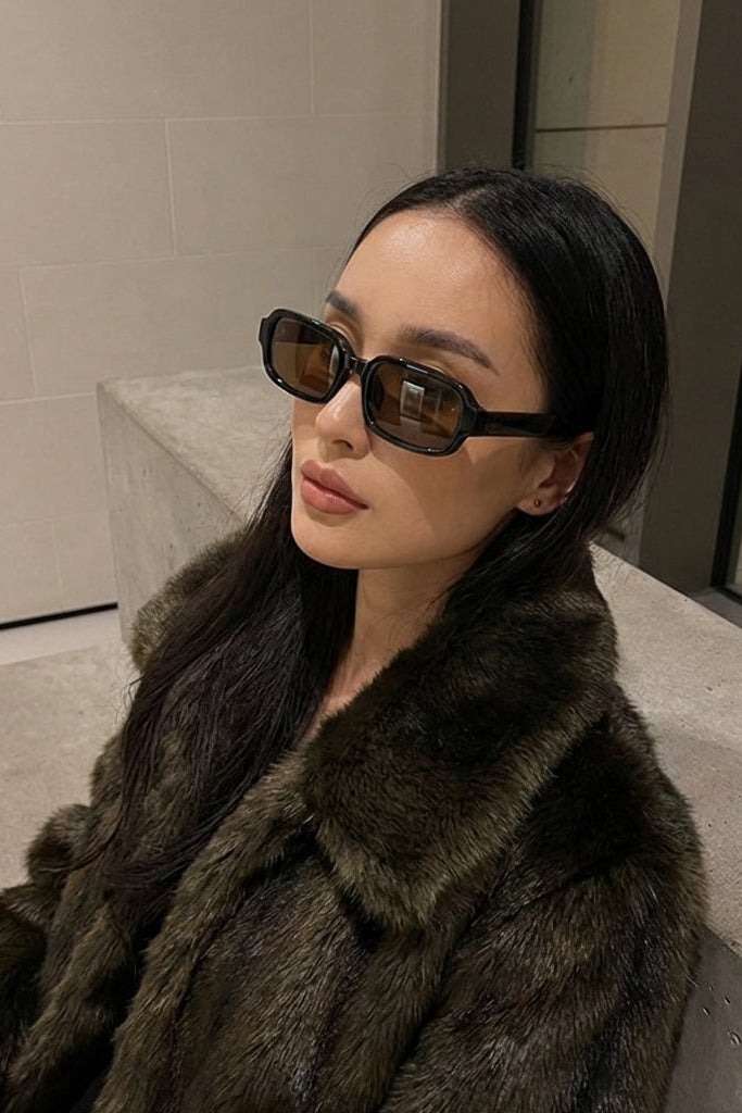 Woman wearing a fur coat and sunglasses in an indoor setting